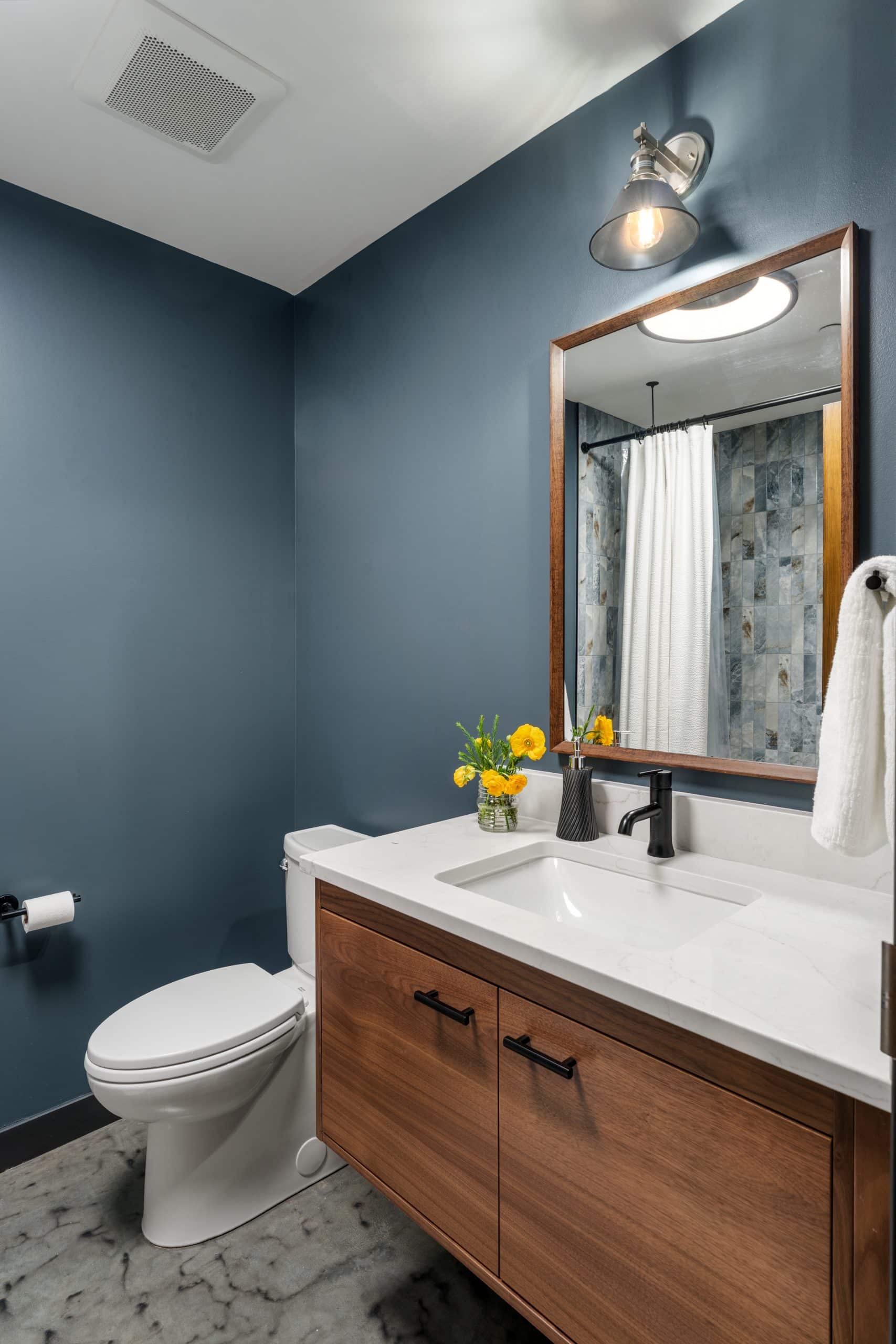 condo bathroom remodel with blue walls and floating wood vanity